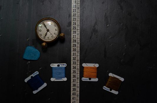 Black background with sewing utensils and a clock