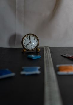 Black background with sewing utensils and a clock
