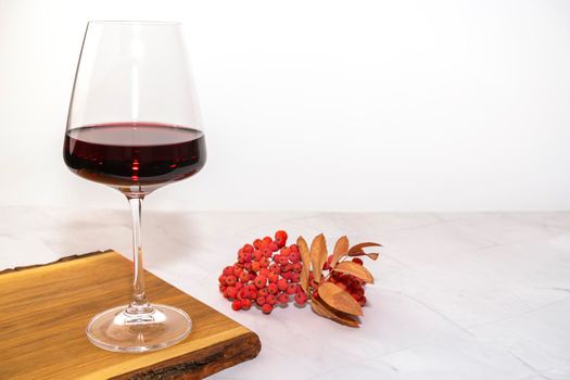 a glass of red wine on a Board with Rowan berries. High quality photo