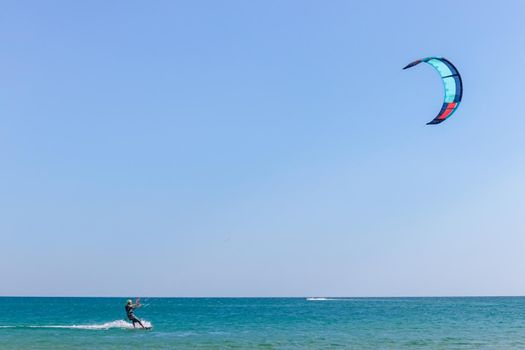 a kitesurfer surfing on the smooth azure water. recreational sport. A Man Rides A Kiteboarding In The Sea Water. extreme sport. High quality photo