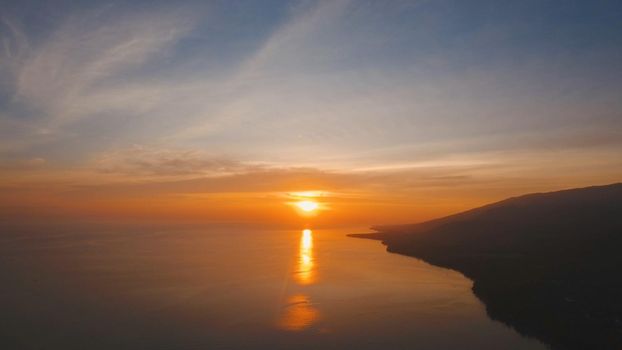 Sea coast at sunset. Aerial view of sunset on the ocean coast, sea, beach, sky, clouds. Bali, Indonesia. Sunset on the island of Bali.