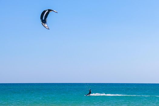 a kitesurfer surfing on the smooth azure water. recreational sport. A Man Rides A Kiteboarding In The Sea Water. extreme sport. High quality photo