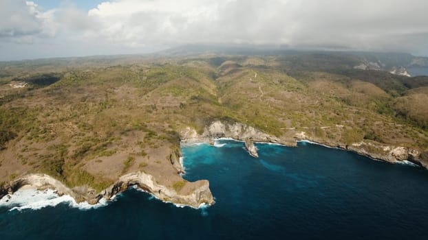 Aerial view of Rocky coast with high cliffs, sea surf with breaking waves on the coast, Nusa Penida, Bali, Indonesia. Ocean with waves and rocky cliff. Travel concept