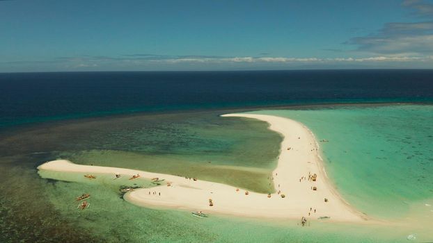 Tropical white island and sandy beach with tourists surrounded by coral reef and blue sea, aerial view. Sandbar Atoll. Island with sand bar and coral reef. Summer and travel vacation concept, Camiguin, Philippines.