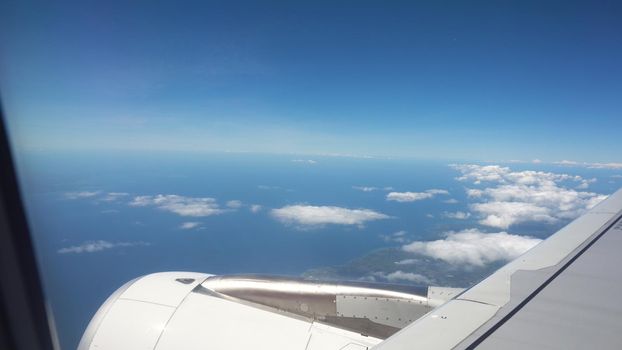 Airplane turbine in the porthole window. Blue sky view from airplane window.