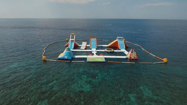Aerial view inflatable Floating Water Park in the sea. Aquapark with slides and attractions in the ocean. Bali, Indonesia.