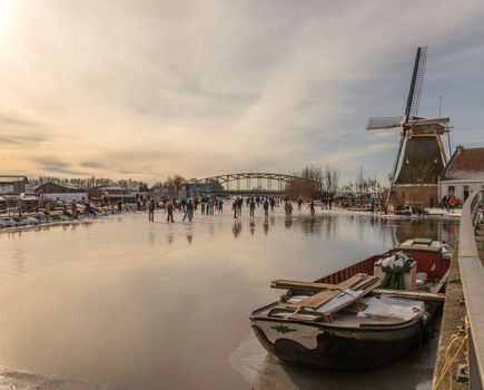 Schipluiden,Holland,14-feb-2021:people skating on the canal near the windmill, it has been years ago that is was so cold in Holland, people can skate