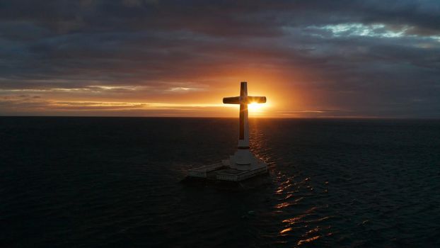 Catholic cross in sunken cemetery in the sea at sunset, aerial view. Colorful bright clouds during sunset over the sea. Sunset at Sunken Cemetery Camiguin Island Philippines.