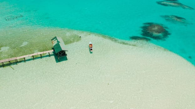 Sandy beach with and azure water, boat of the lagoon,copy space for text, top view. Sea water surface in lagoon. Transparent turquoise ocean water surface. Background texture