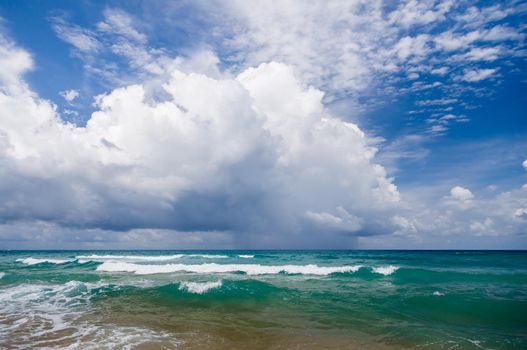 Seascape, small waves with white foam at the top against the background of blue water. Low, dense clouds cover the sky. A great place to relax and reflect