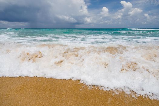 Powerful, stormy, foamy waves are picked up by the wind. White foam from bubbles of different sizes is scattered to the sides and spreads all over the beach. Close-up.