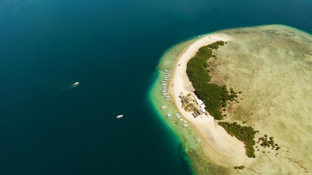 Tropical island and sandy beach with tourists surrounded by coral reef and blue sea in honda bay, aerial view. Island with sand bar and coral reef. starfish island. Summer and travel vacation concept, Philippines, Palawan