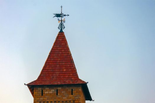 the spire of the tower with a weather vane against the blue sky. High quality photo