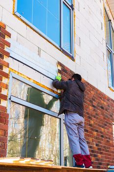 A man works with a drill, attaches thermal panels made of clinker to the facade of the house. Clinker bricks and tiles in brown color