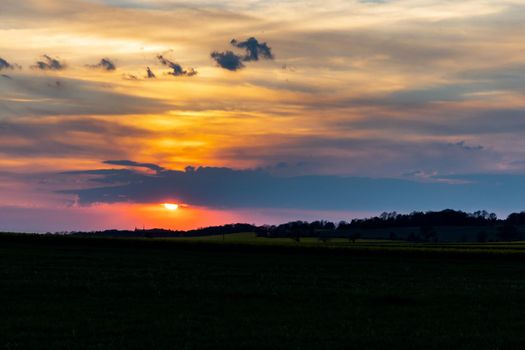 Green and yellow fields of colza at cloudy sunset