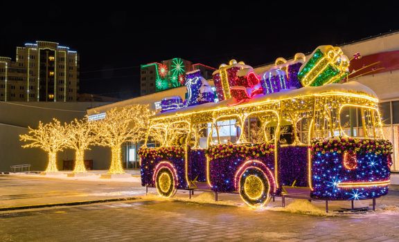 New Year's illumination of the city at dusk. Decorative trees, arches, pavilions in garlands.