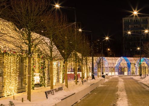 New Year's illumination of the city at dusk. Decorative trees, arches, pavilions in garlands.