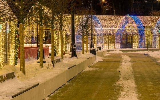 New Year's illumination of the city at dusk. Decorative trees, arches, pavilions in garlands.