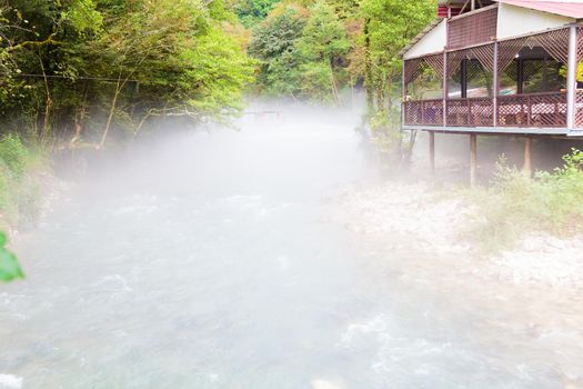 Gazebo on the river bank in the early morning. Fog on the water. Hot summer, cold water.