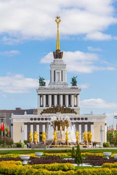 MOSCOW, RUSSIA-MAY 12, 2016: Peoples ' Friendship Fountain in VDNH Park in Moscow. Gorgeous view of the gilded fountain on the background of a tall building.