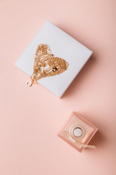 A gift for Valentine's Day. Perfume and a box with a gold chain on a pink background.
