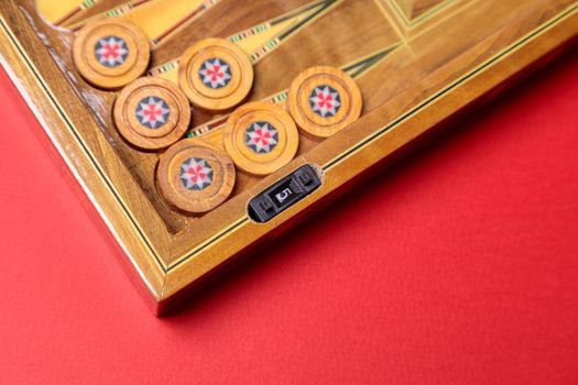 An entertaining game of backgammon on a red background. Checkers, cubes, handmade board