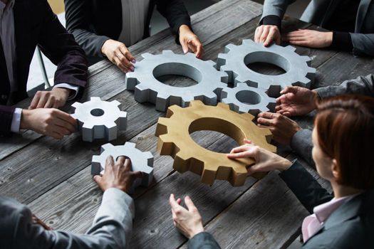 Business people connect gear together at meeting table, success cooperation teamwork concept