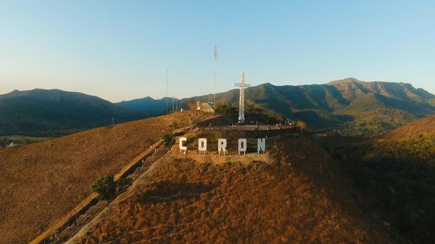 The sign of the city of Coron is on a hill, a famous tourist place. Aerial view: Catholic cross on a hill, mountain in the town of Coron, Philippines,Palawan Busuanga. Travel concept.