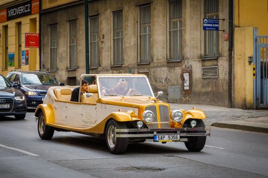 Czech Republic 14 april 2018 Vintage cars for tourist excursions. Yellow convertible car on the road with tourists.