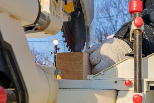 A male worker on the street in winter cuts a block with an angle electric saw with a sharp blade.