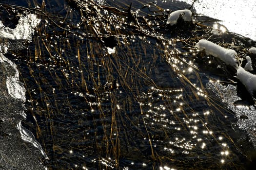 little creek in winter with ice in backlit