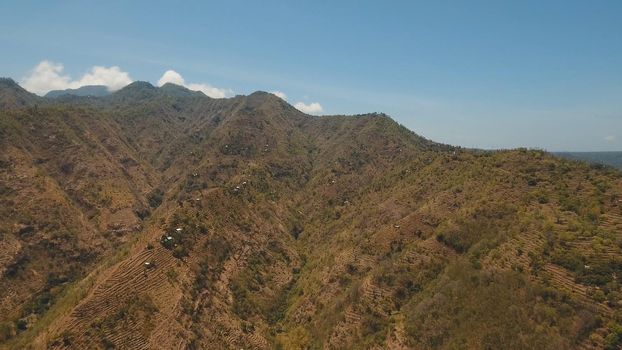 Aerial view of landscape, mountains covered with green forest, trees with sky and clouds, Bali,Indonesia. Slopes of the mountains are covered with forest in Asia. Travel concept.