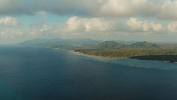 Seascape: Coast of tropical island covered by jungle with beautiful clouds, top view. Balabac, Palawan, Philippines. Summer and travel vacation concept.