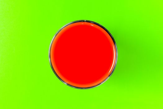 a glass of tomato juice on a green background. hard shadow. the view from the top. isolate. High quality photo