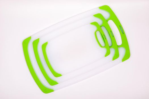 Set of white kitchen cutting boards with green handles for cooking. For cutting food, vegetables, meat, fish. Durable, professional, white plastic.
