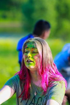 Russia, Moscow - June 25, 2017. Portrait of a girl with bright flowers on her face. Laughs with happiness. Holi is a traditional holiday in India