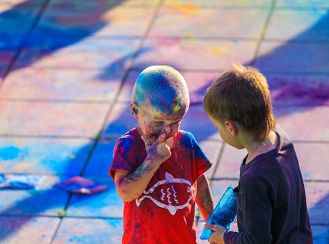 Russia, Moscow - June 25, 2017. Little boy with bright colors on his face. Laughs with happiness. Holi is a traditional holiday in India