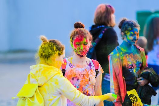 Russia, Moscow - June 25, 2017. Portrait of a girl with bright flowers on her face. Laughs with happiness. Holi is a traditional holiday in India