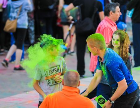 Russia, Moscow - June 25, 2017. Cheerful, young people throw themselves bright colors. Happy faces of adults and children are stained with paint. Holi is a traditional holiday in India