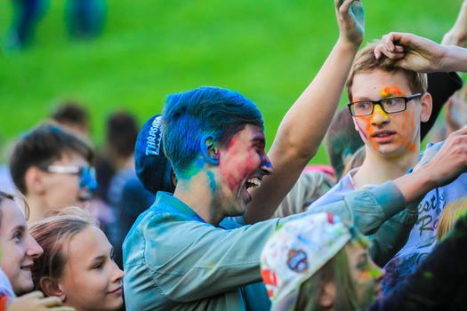 Russia, Moscow - June 25, 2017. Portrait of a young man with bright colors on his face. Laughs with happiness. Holi is a traditional holiday in India