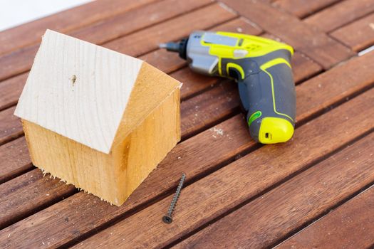 On the table is a modern miniature working tool for screwdriving screws. Craft from wooden bars.