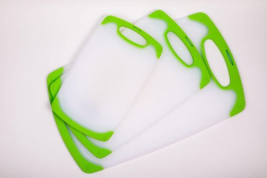 Set of white kitchen cutting boards with green handles for cooking. For cutting food, vegetables, meat, fish. Durable, professional, white plastic.