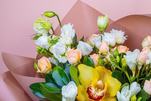 Fresh bouquet in pastel shades of pink, white, green, yellow. Homogeneous pink, blue background. Delicate bouquet for a woman.