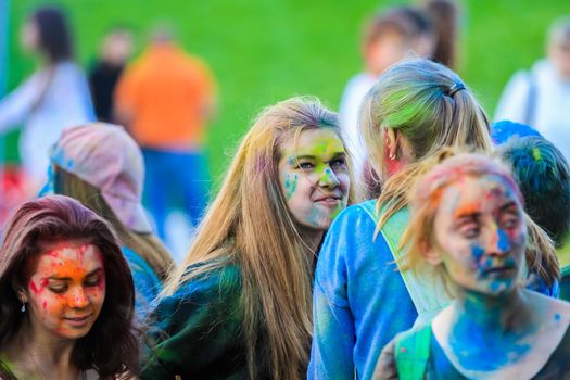 Russia, Moscow - June 25, 2017. Portrait of a girl with bright flowers on her face. Laughs with happiness. Holi is a traditional holiday in India