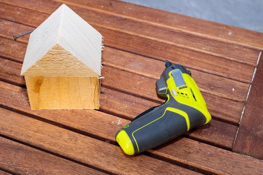 On the table is a modern miniature working tool for screwdriving screws. Craft from wooden bars.