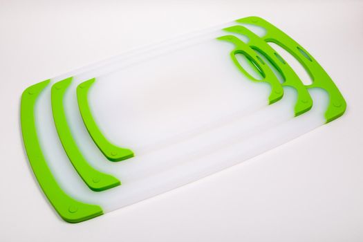 Set of white kitchen cutting boards with green handles for cooking. For cutting food, vegetables, meat, fish. Durable, professional, white plastic.