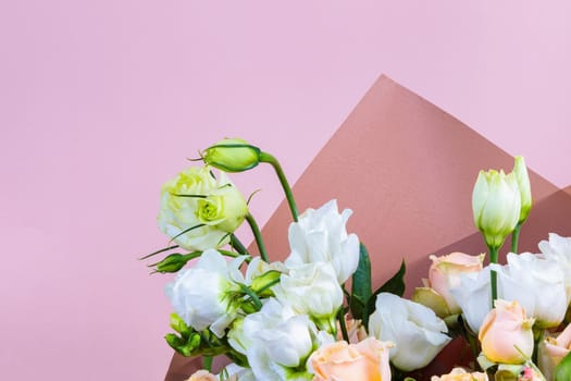 Fresh bouquet in pastel shades of pink, white, green, yellow. Homogeneous pink, blue background. Delicate bouquet for a woman.