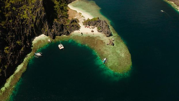 Tropical lagoon with sandy beach surrounded by cliffs, aerial view. El nido, Philippines, Palawan. Seascape with tropical rocky islands, ocean blue water. Summer and travel vacation concept