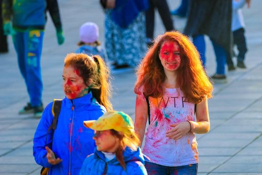 Russia, Moscow - June 25, 2017. Portrait of a girl with bright flowers on her face. Laughs with happiness. Holi is a traditional holiday in India