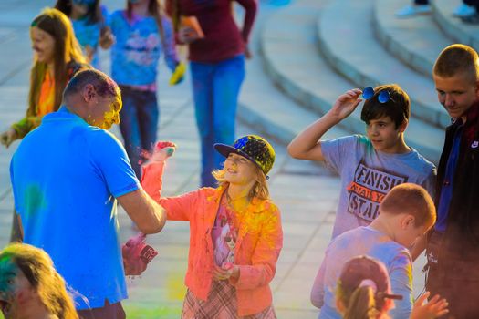 Russia, Moscow - June 25, 2017. Cheerful, young people throw themselves bright colors. Happy faces of adults and children are stained with paint. Holi is a traditional holiday in India